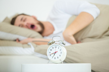 man with alarm clock in bedroom