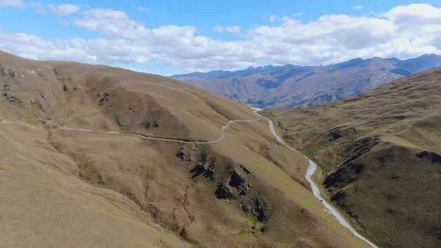 Stunning high angle aerial drone flight over the Crowns Range & the road passing through it near Cardrona, located between the popular tourist towns Queenstown & Wanaka on New Zealand's South Island.