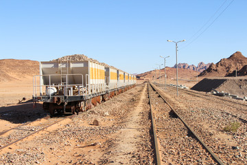 Group of yellow wagons with material for nitrogen fertilizers stands on railroad in desert in...
