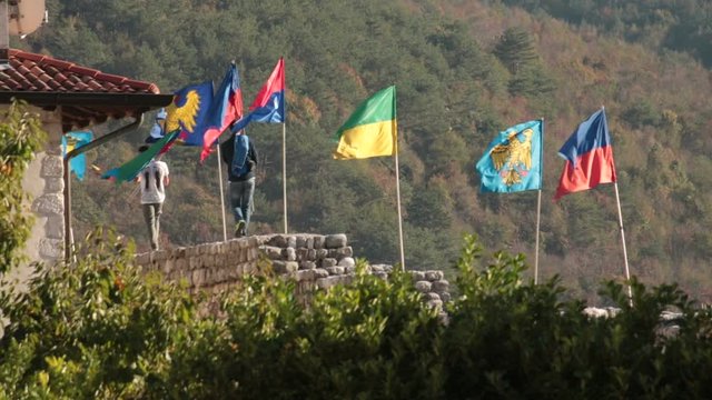 two people move flags, the guys are on an ancient medieval wall in Venzone (italy)