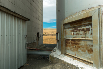 A View of a Farm Field Between Storage Bins at a Grain Elevator