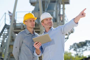 two smart businessman holding tablet and document pointing outdoors