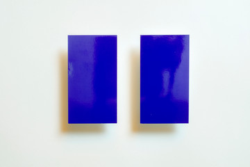Two blue blank gloss linear textured business cards flying and isolated on white paper background, us standard size 3.5 x 2 inches, real non professional studio photo.