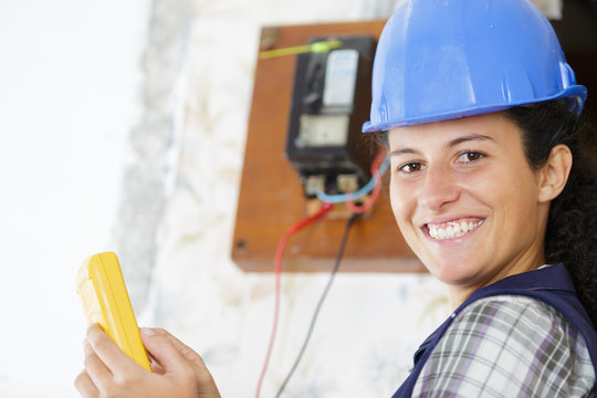 happy young female woker measuring electrical current