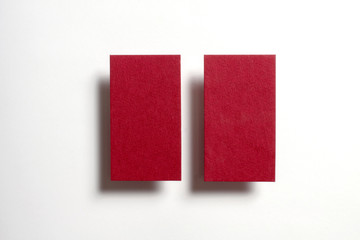 Two red blank matt linear textured business cards flying and isolated on white paper background, us standard size 3.5 x 2 inches, real non professional studio photo.