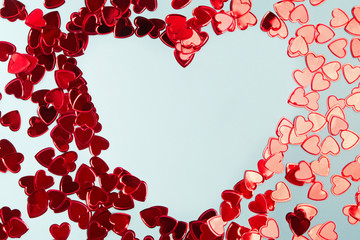Red foil confetti arranged into a heart shaped frame on blue background.