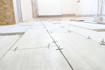 Fototapeta na wymiar Close up shot of unfinished floor tiles installation in kitchen