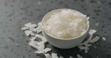 coconut chips in white bowl on terrazzo surface