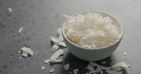 coconut chips in white bowl on terrazzo surface