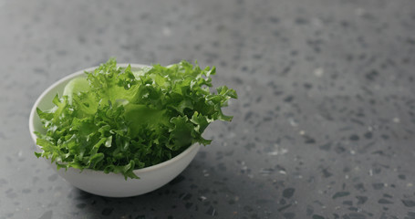 frisee leaves in white bowl on terrazzo surface