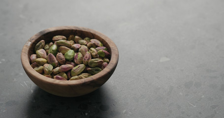 peeled pistachios in olive bowl on terrazzo surface