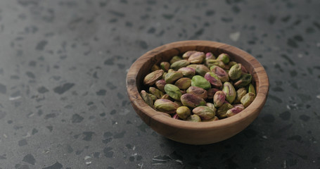 peeled pistachios in olive bowl on terrazzo surface