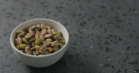 peeled pistachios in white bowl on terrazzo surface
