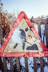 Old roadworks ahead road sign partially covered with snow in the village