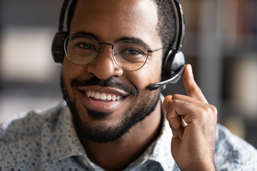 Happy friendly african telemarketing operator wear wireless headset portrait