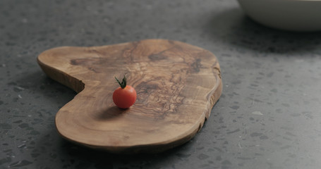 single cherry tomatoe on olive board