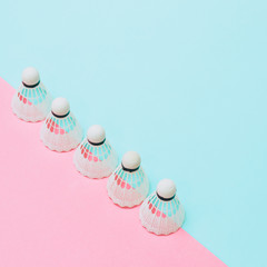 A line of badminton shuttlecocks on a blue and pink background. Geometric concept. Empty space for...