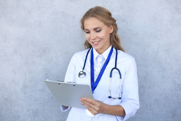 Smiling female doctor with stethoscope holding health card isolated over grey background.