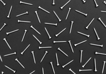 Industrial background of metal hex bolts on black background.