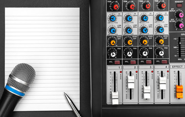 Notepad with audio sound mixer and microphone on black. Top view. Space for text.