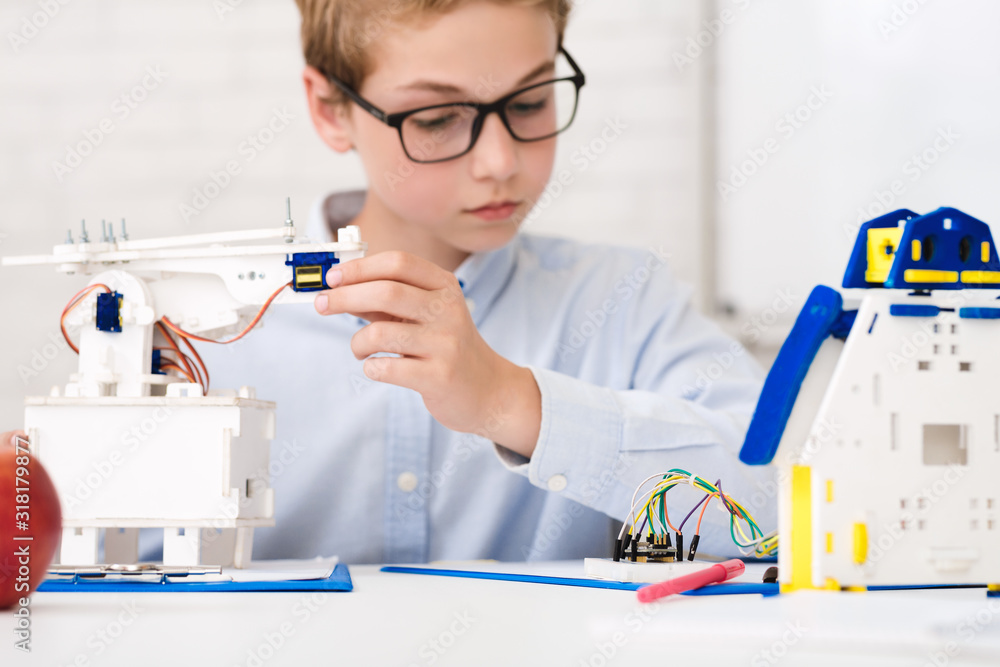Poster Smart schoolboy at stem lesson constructing robots