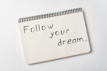 Notepad with the words Follow your dream on white background. Handwritten