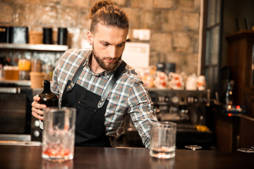 Handsome barman is holding an open bottle