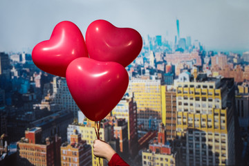 Valentines day in the New York city. woman hand holding three red balloons in form of heart over Manhattan and skyscrapers. Сoncept. America. USA. Aerial view.