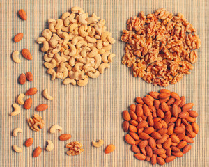Background of different nuts (cashew, almonds, walnuts)  in shapes of a circle on a straw mat with...