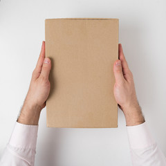 Rectangular box on men's hands on white background. Top view. Vertical frame
