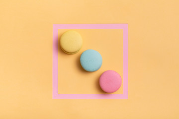 Hipster colorful macaroons on summer yellow background. French pastry. Top view, flat lay