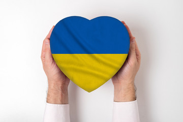 Flag of Ukraine on a heart shaped box in a male hands. White background
