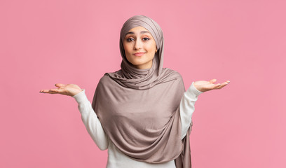 Unsure Muslim Woman In Hijab Shrugging Shoulders On Pink Studio Background