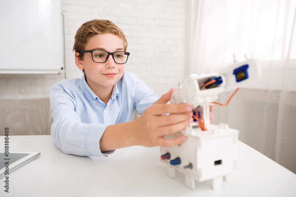 Poster Clever schoolboy constructing robot at stem educational class