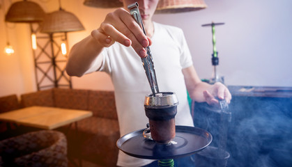 Cooking hookah in the bar. Young man with hookah in restaurant