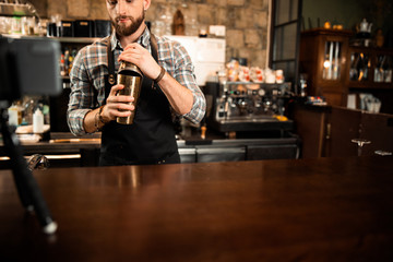 Bearded barman is making alcoholic cocktail behind the bar