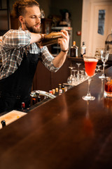 Young barman mixing cocktail while working at bar