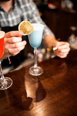 Male bartender serving fresh delicious blue cocktail