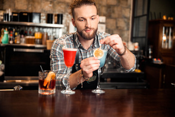 Bartender is standing near three different cocktails