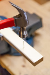 Mit Hammer einen Nagel in ein Brett schlagen