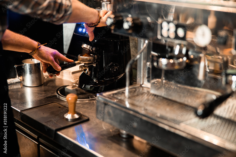 Wall mural Cropped photo of barista tamping ground coffee