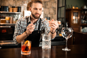 Busy young bartender is wearing uniform indoors