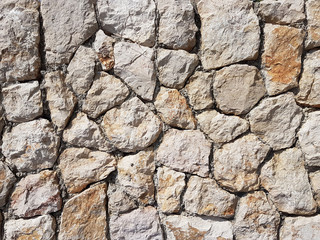 Ancient medieval stone masonry. Texture of a fragment of a wall of an old structure. A background for design and creative work. Decoration and exterior decoration of the building. Construction works