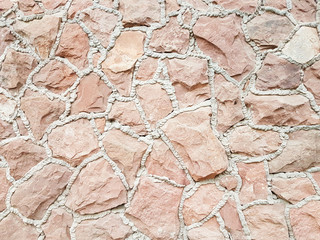 Ancient medieval stone masonry. Texture of a fragment of a wall of an old structure. A background for design and creative work. Decoration and exterior decoration of the building. Construction works