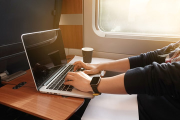    Young girl  hand with smartwatch which  traveling by train and working on laptop. Business travel concept.