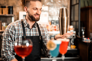 Smiling young bartender is mixing a fancy cocktail