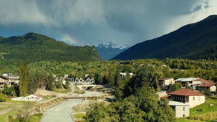 Fototapeta na wymiar rainbow in the mountains above the river and the town of Mestia in mountain Svaneti on an autumn day