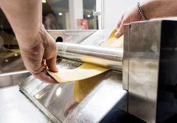 Chef rolling dough with a pasta machine. Pasta maker machine. 