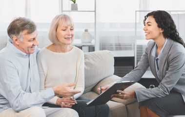 Senior couple consulting with adviser at office
