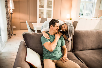Fototapeta premium Smiling pretty woman hugging her husband at home